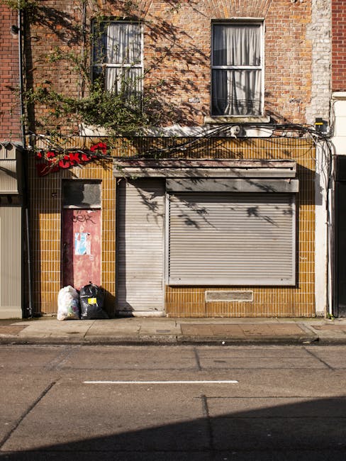 A street scene on Portobello Road in Notting Hill W11, featuring a decorative banner stretched across the road with Union Jack flags on either side and a white central sign displaying the street name.
